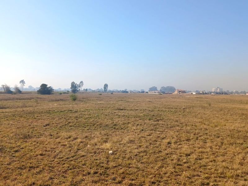 A wide, open expanse of vacant residential land featuring natural grass cover and distant horizon views.