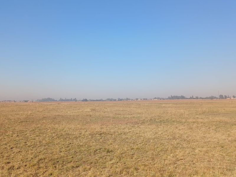 A wide, open expanse of vacant residential land featuring flat terrain and clear horizon views.