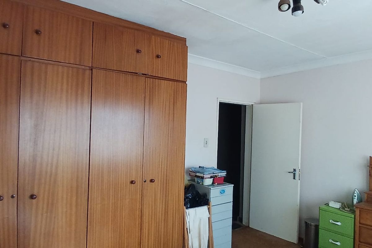 A bedroom featuring built-in wooden cupboards with overhead storage and a standard interior door.