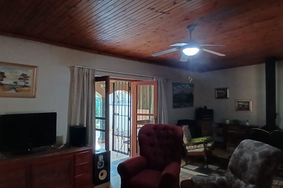 A cozy living room featuring a warm timber-clad ceiling, a built-in fireplace, and direct access to an outdoor patio area.