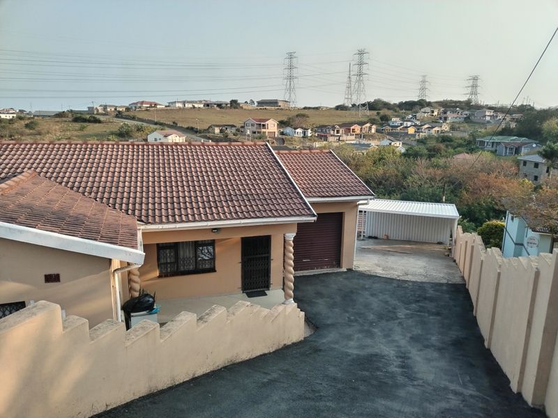 Elevated view of a residential property featuring a tiled roof, paved driveway, garage, and perimeter boundary walls in a suburban setting.