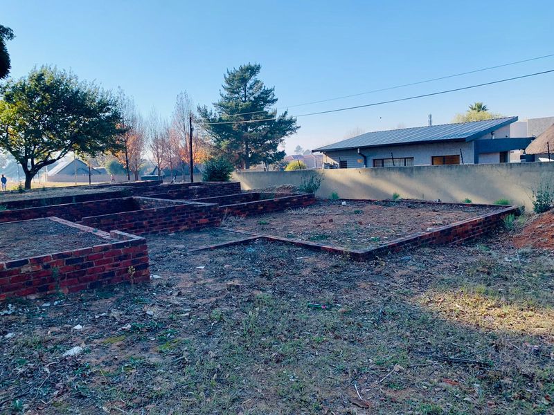 Vacant residential land featuring partial brick foundation walls and perimeter boundary walling with electric fencing, suitable for development.