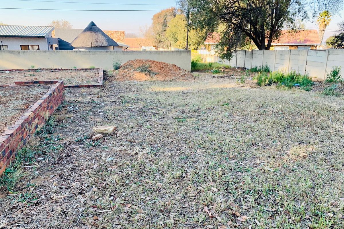 A vacant residential plot featuring a brick retaining wall and precast concrete boundary fencing, offering a blank canvas for landscaping or development.