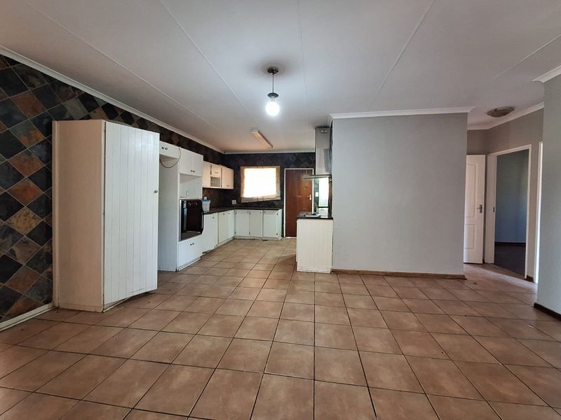 Spacious kitchen featuring built-in cabinetry, tiled flooring, and a tiled splashback, offering a functional layout ready for modern updates.