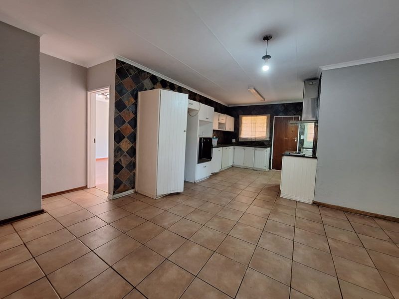 Spacious kitchen featuring tiled flooring, built-in cabinetry, integrated oven, and a distinctive slate tile backsplash, offering a functional layout ready for modernization.