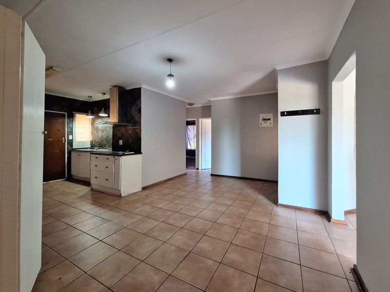 An open-plan living and kitchen area featuring tiled flooring, built-in cabinetry with an extractor fan, and neutral wall finishes.