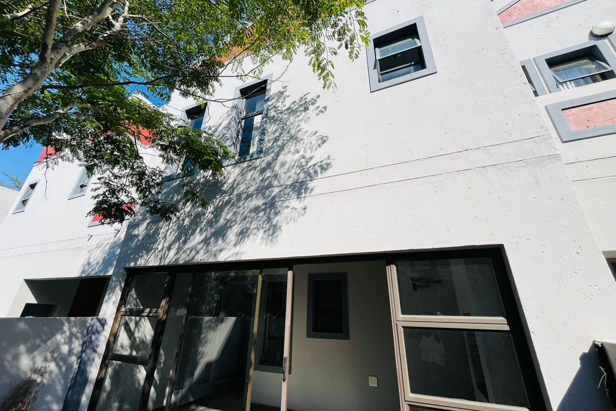 Rear elevation of a multi-story apartment building featuring large sliding glass doors leading to a patio area and modern casement windows.
