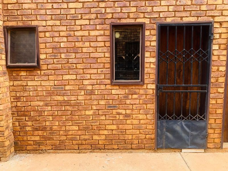 Exterior view of a face brick wall featuring a security gate and two window frames.