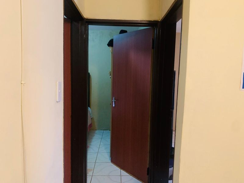 A view through a doorway into a bedroom, featuring tiled flooring and dark wood-finish internal doors.