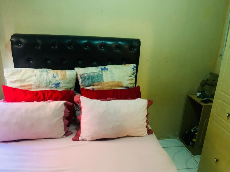 A bedroom featuring a built-in wardrobe and plain wall finishes, currently showing signs of wear and needing cosmetic updates.