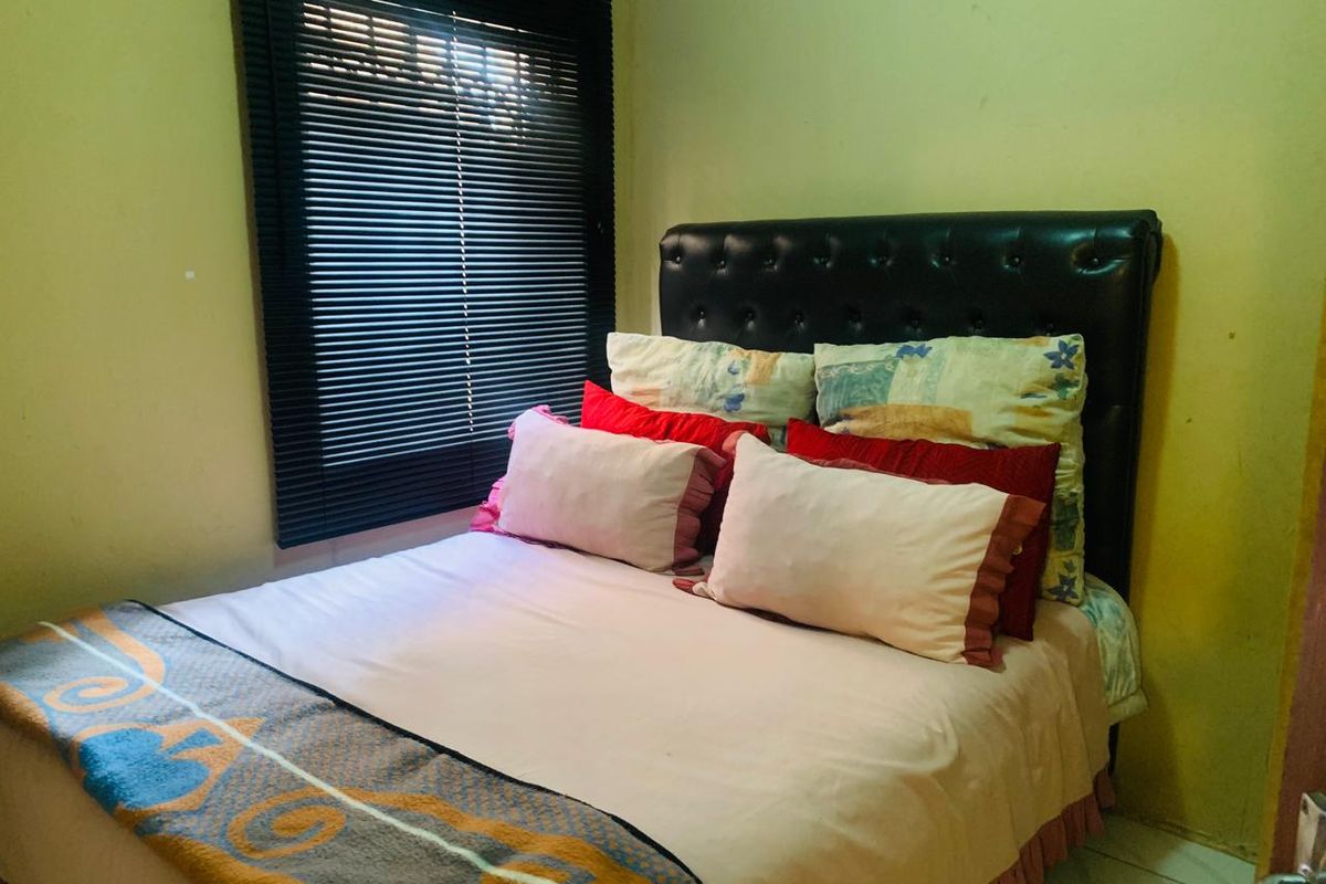 A compact bedroom featuring tiled flooring and dark venetian blinds. The space would benefit from a fresh coat of paint to improve its overall condition.