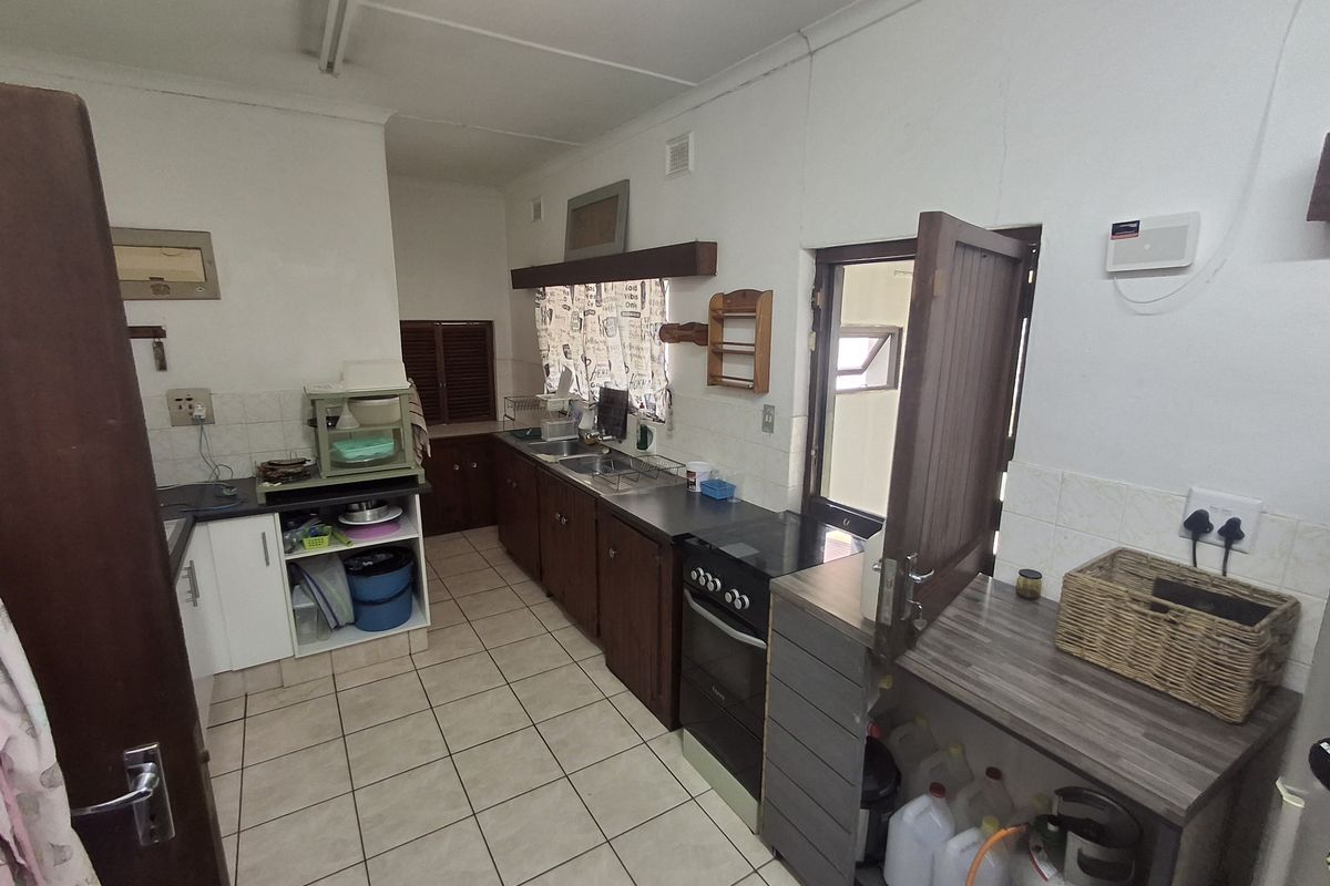 Functional kitchen featuring dark wood cabinetry, tiled flooring, built-in oven, and direct access to an exterior area.