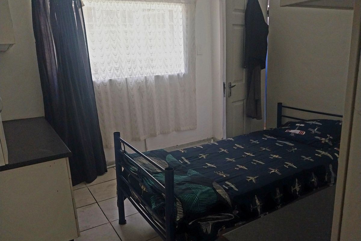 A functional bedroom featuring tiled flooring and a window, providing a simple and practical living space.