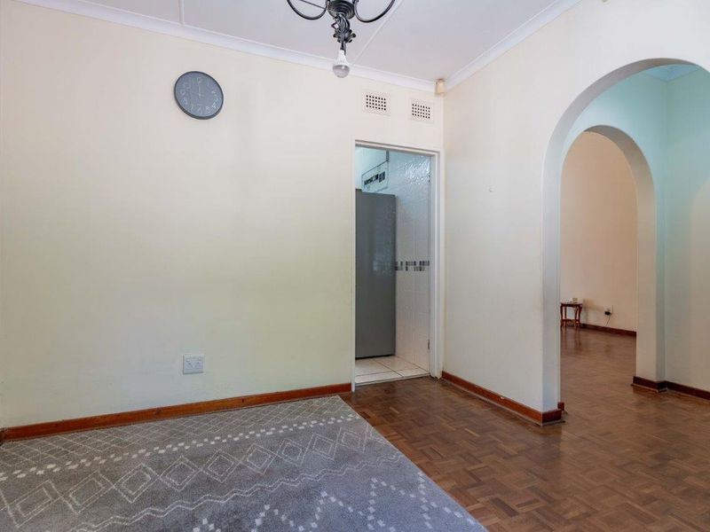 A bright living area featuring classic parquet flooring, a decorative archway leading to adjacent space, and a coved ceiling.