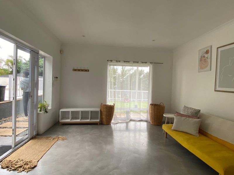 Bright living room featuring polished concrete floors and large sliding glass doors providing direct access to the outdoor patio area.