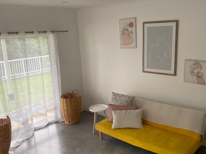A bright living room featuring polished concrete flooring and a large sliding glass door providing direct access to the outdoor patio area.