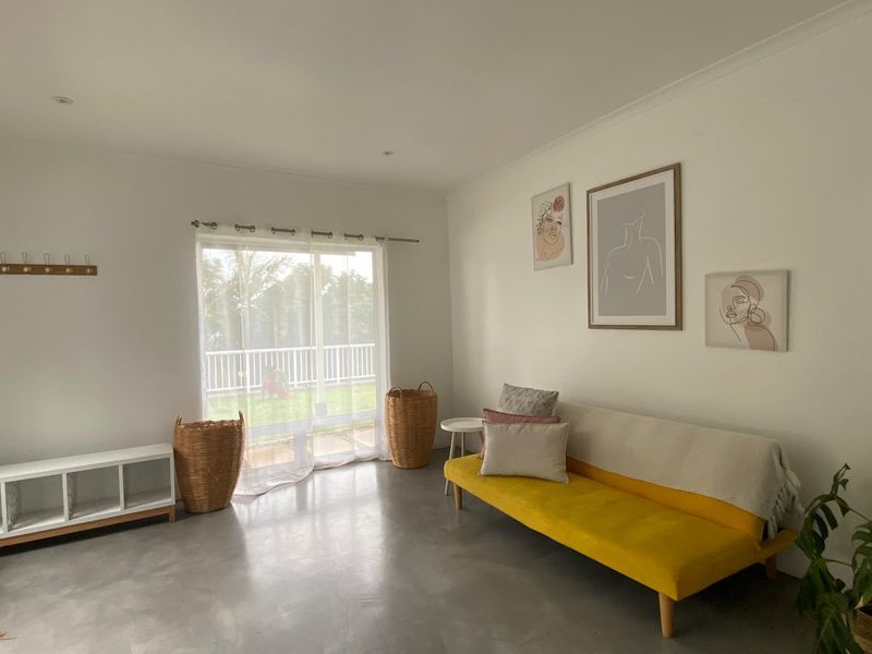 A bright living room featuring polished concrete floors and a large sliding glass door providing access to the outdoor area.
