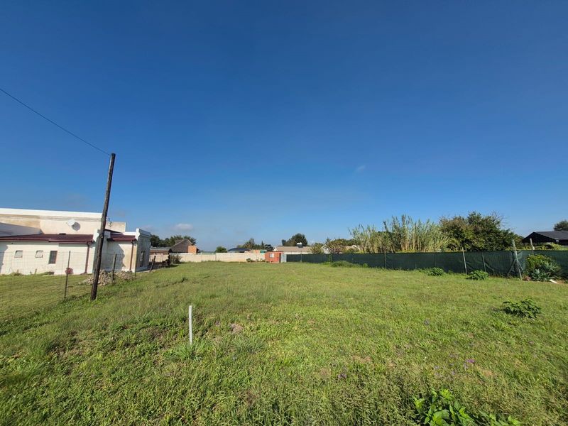 A vacant residential plot featuring open grass, perimeter fencing, and a utility pole, offering a clear space for potential development.