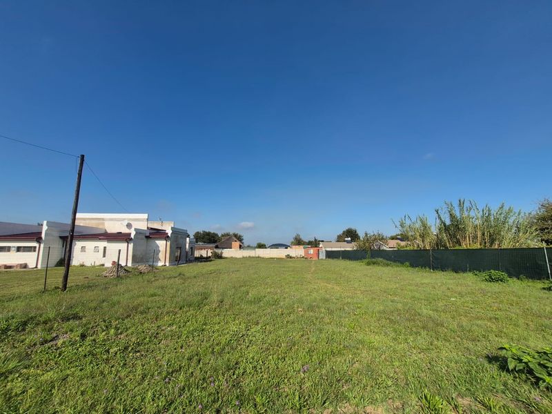 A spacious, level vacant residential plot featuring established perimeter fencing and boundary walls, offering a clear area for potential development.