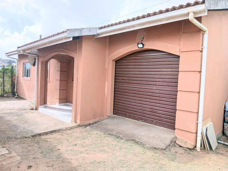 Front elevation of a cottage featuring a roller shutter garage door, tiled roof, and concrete driveway access.
