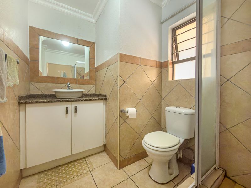 A functional bathroom featuring a vanity with a vessel sink, granite countertop, toilet, and a separate shower enclosure with tiled finishes.