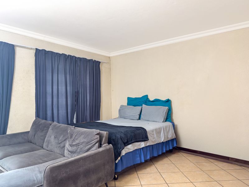 A bedroom featuring tiled flooring and cove cornicing, providing a functional space ready for cosmetic updates.