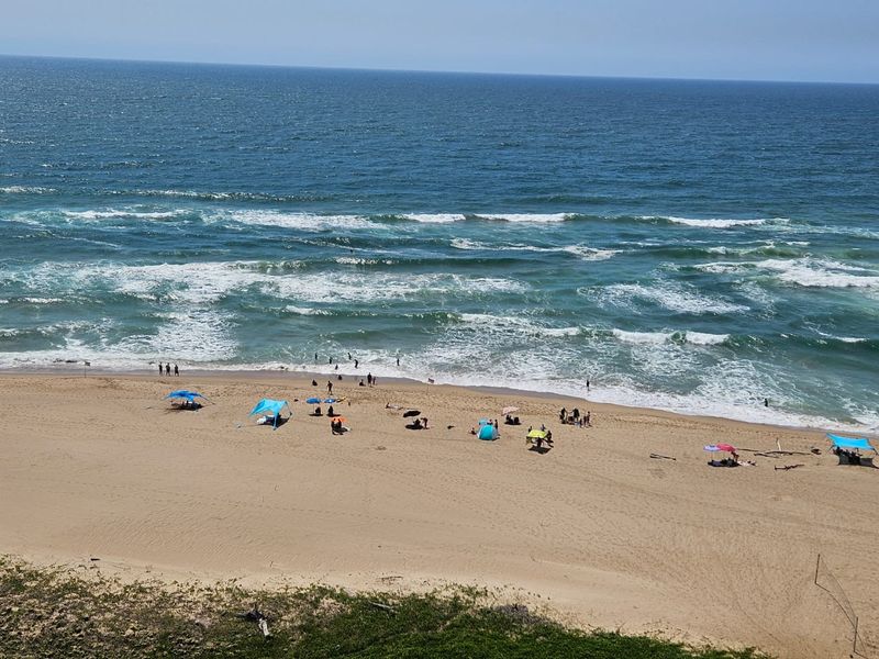 A scenic elevated view of the ocean and sandy beach, highlighting the property's prime coastal location and direct access to the shoreline.