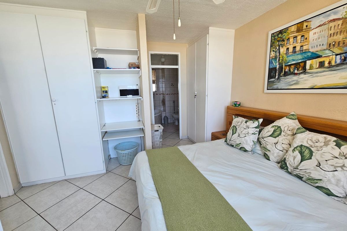 A bedroom featuring built-in wardrobes, tiled flooring, and an en-suite bathroom access point.