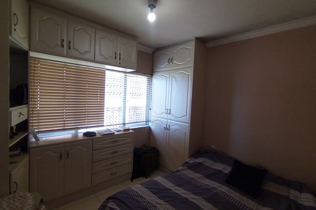 A bedroom featuring extensive built-in cabinetry, including overhead storage and a floor-to-ceiling wardrobe, providing ample storage space.