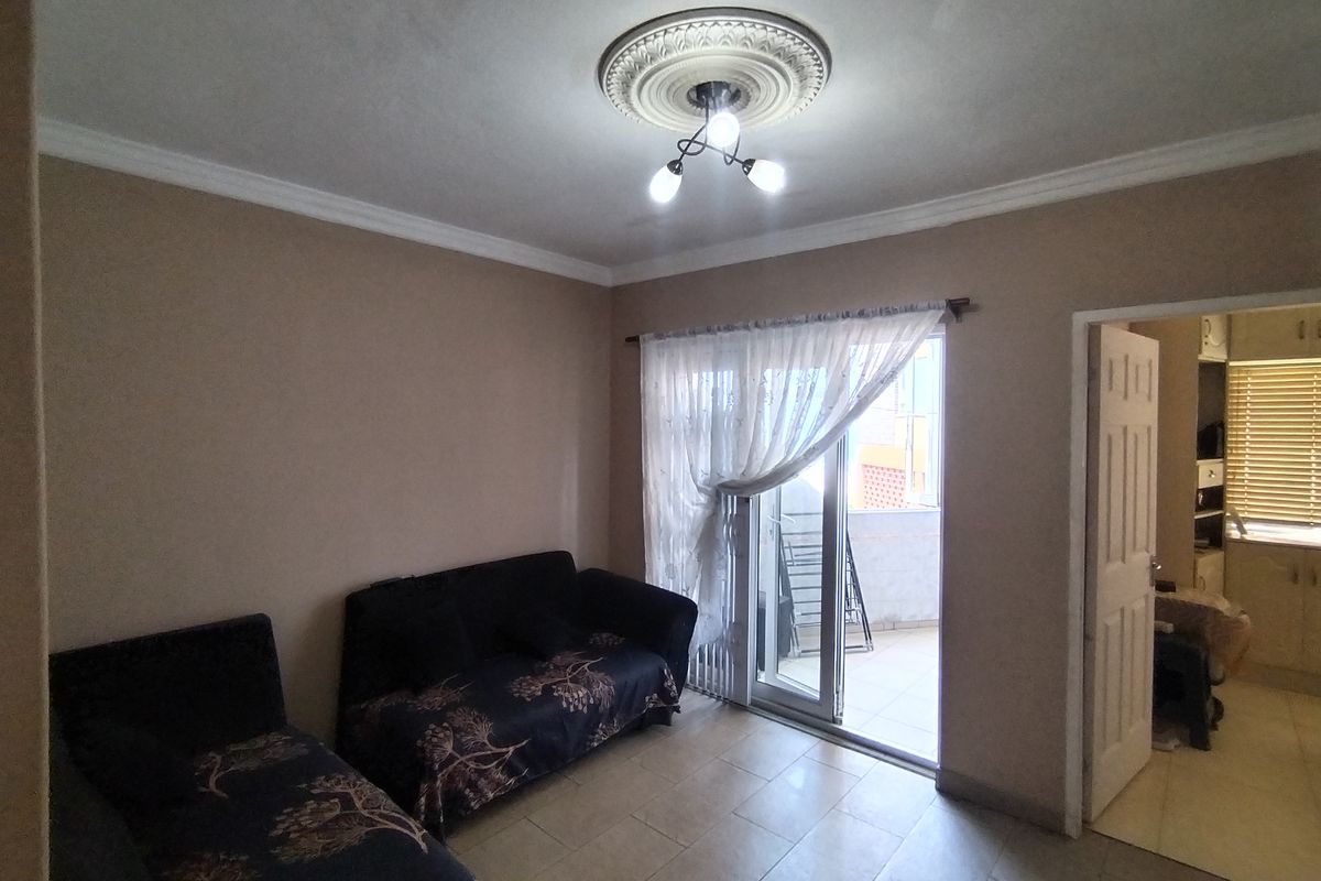 A living room featuring tiled flooring, decorative ceiling rose, and sliding glass doors providing access to an outdoor balcony area.