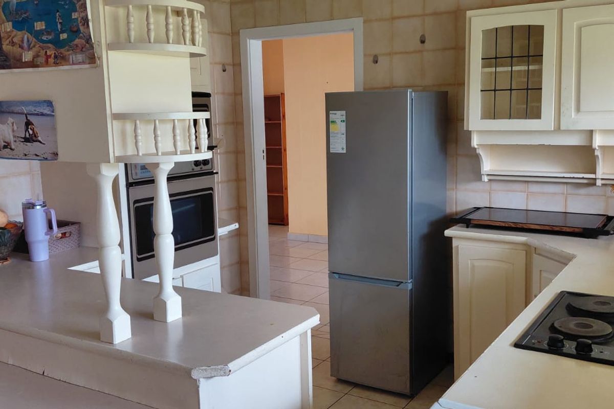 A dated kitchen featuring built-in cabinetry, a wall-mounted oven, and a hob, offering a functional layout with potential for modernization.
