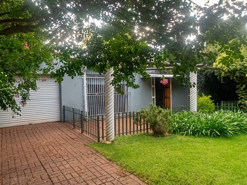 Front exterior view of the property featuring a paved driveway, roller garage door, and a covered entrance area with decorative columns.