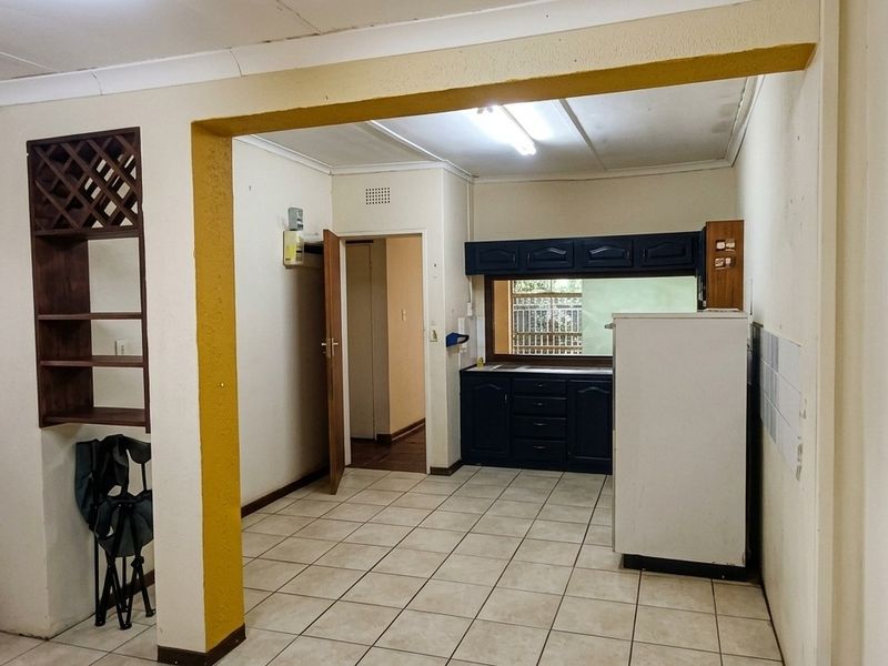 A functional kitchen area featuring tiled flooring, built-in cabinetry, and a convenient pass-through window, offering a blank canvas for modern updates.