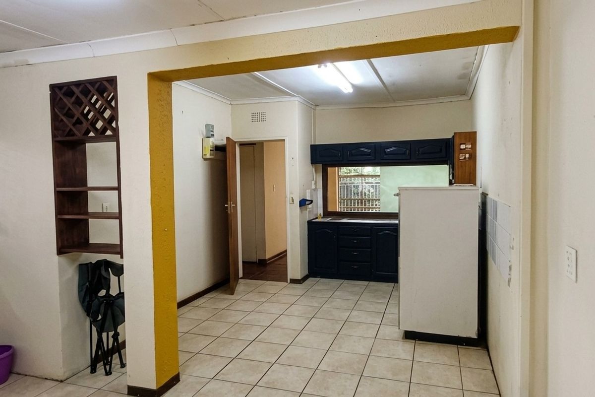 A functional kitchen area featuring tiled flooring, built-in cabinetry, and a convenient pass-through window, offering a blank canvas for modern updates.