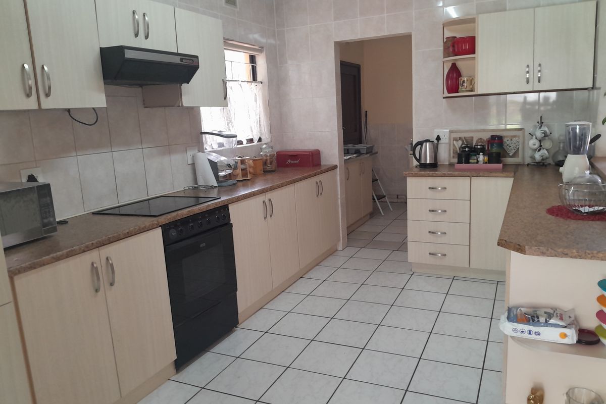 A functional kitchen featuring light-toned cabinetry, tiled splashbacks, a built-in oven with extractor fan, and a connected scullery area.