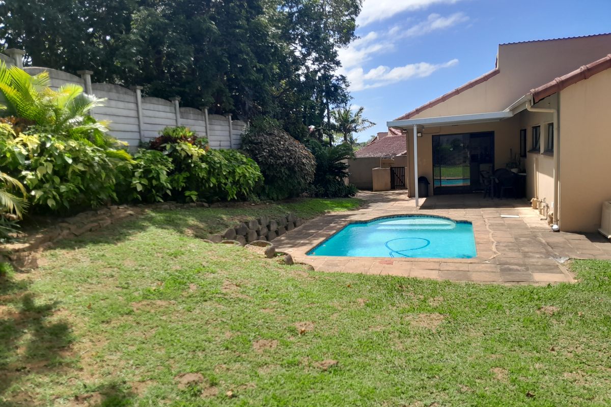 A private rear garden featuring a swimming pool, paved patio area, and established landscaping, providing a functional outdoor space for the townhouse.
