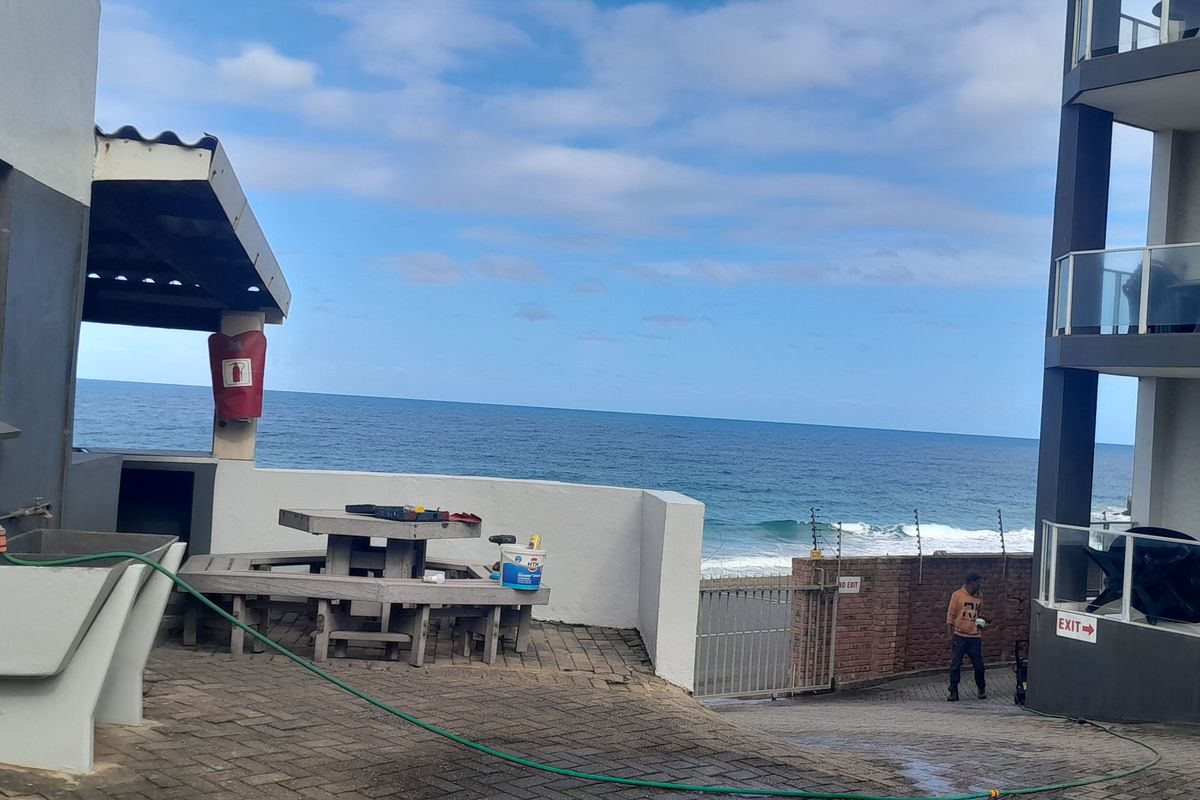 Outdoor communal area featuring paved flooring, a built-in utility sink, and direct ocean views, situated between apartment building blocks.