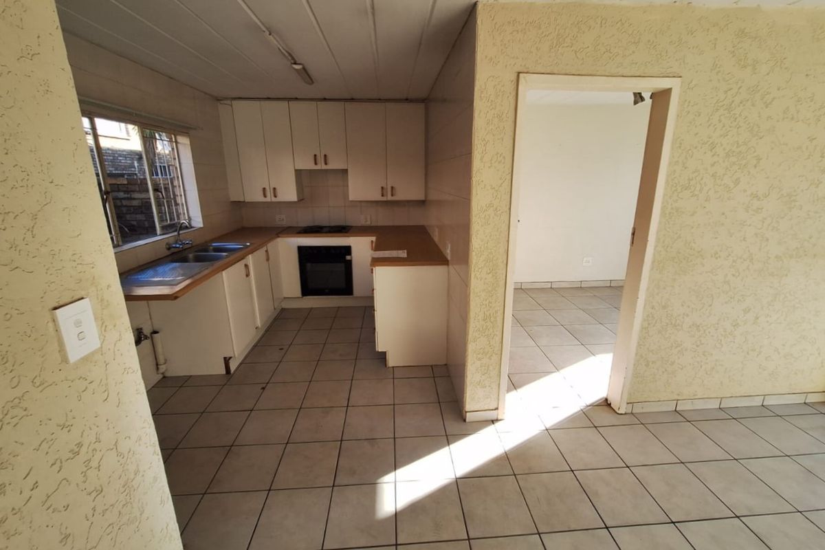 A functional kitchen featuring built-in cabinetry, laminate countertops, a double basin sink, and integrated oven and hob, with tiled flooring throughout.