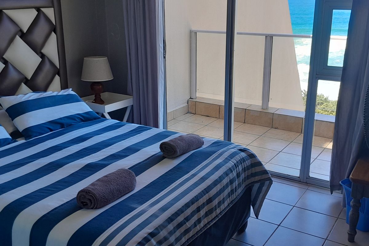 Bedroom featuring tiled flooring and direct access to a private balcony with ocean views through large sliding glass doors.