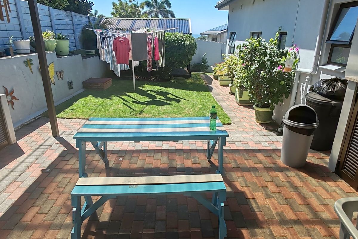 A rear garden area featuring a paved patio, built-in outdoor sink with cabinetry, and a small lawn space.