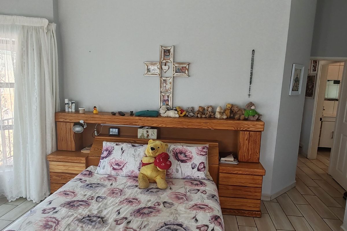 A bedroom featuring a built-in wooden headboard with integrated bedside tables, tiled flooring, and access to an outdoor area through a sliding glass door.
