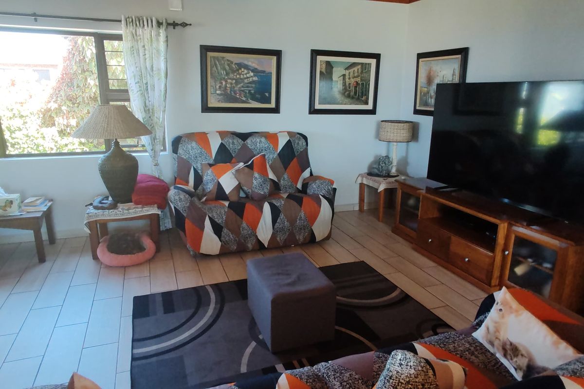 A comfortable living room featuring tiled flooring and a large window that provides natural light to the space.