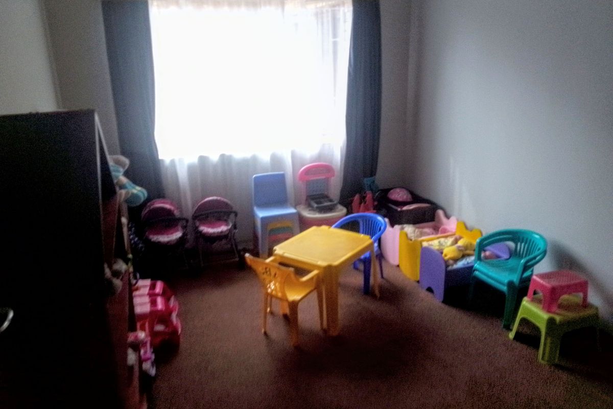 A bedroom featuring carpeted flooring and a window with curtain fixtures, currently utilized as a play area.