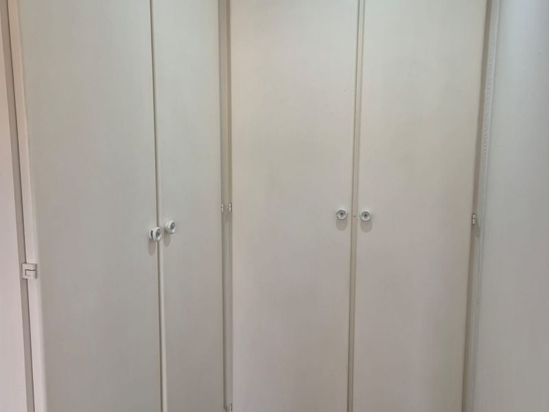 A clean hallway featuring built-in storage cupboards and dark laminate flooring.
