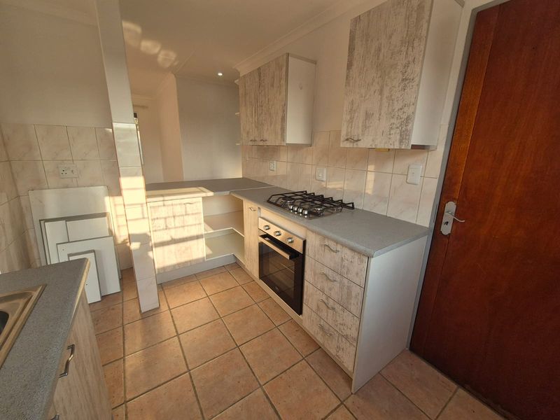 A functional kitchen featuring built-in cabinetry, a gas hob, and an integrated oven, finished with tiled flooring and a tiled backsplash.
