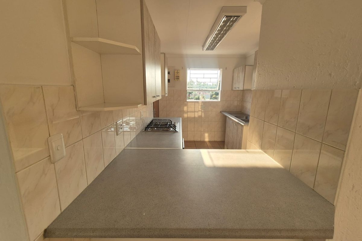 A functional kitchen featuring built-in cabinetry, laminate countertops, a gas hob, and tiled splashbacks, offering a clean and practical workspace.