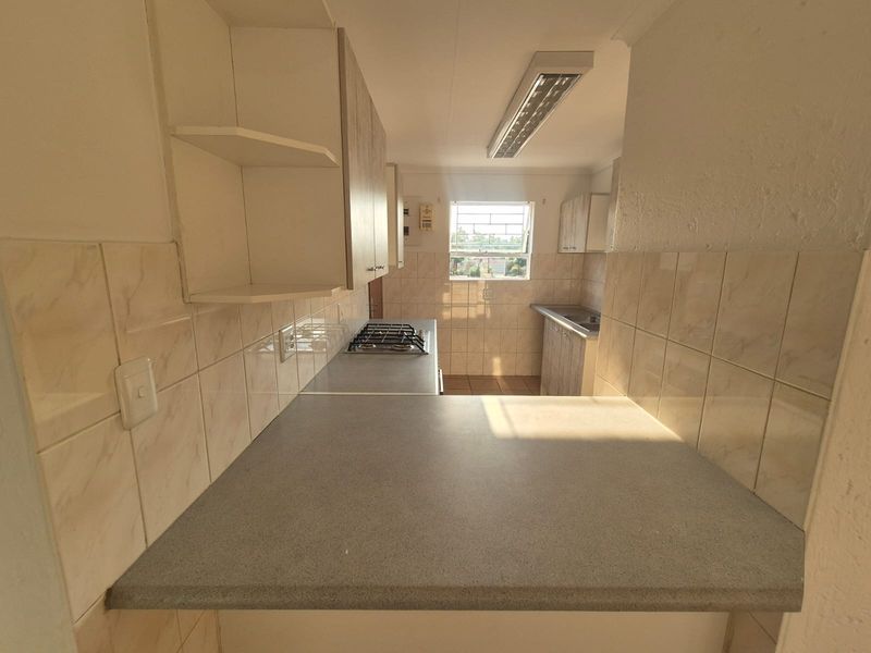 A functional kitchen featuring built-in cabinetry, laminate countertops, a gas hob, and tiled splashbacks, offering a clean and practical workspace.