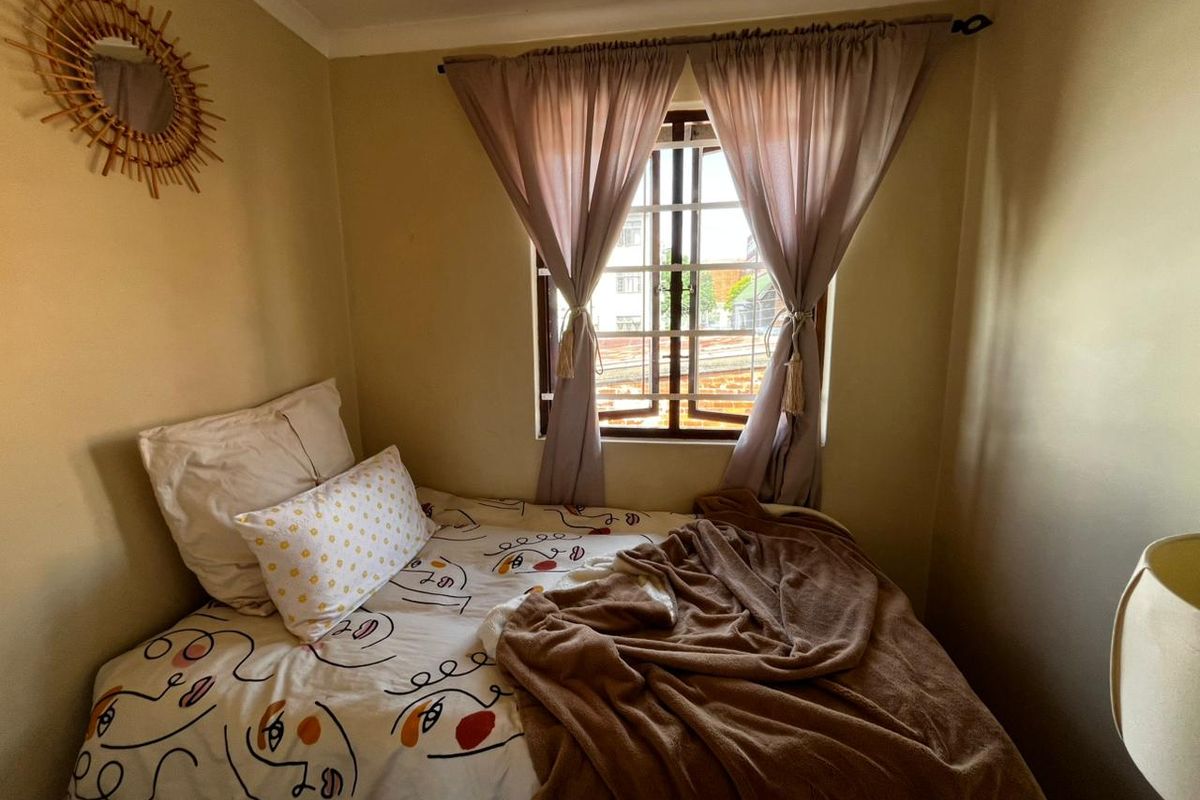A cozy bedroom featuring a window with security bars and decorative coving, providing a comfortable and functional sleeping space.