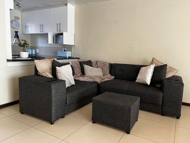 Open-plan living area featuring tiled flooring and a compact kitchen with built-in cabinetry and granite countertops.