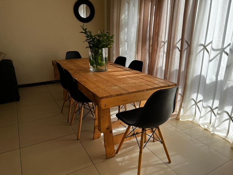 A bright dining area featuring neutral tiled flooring and floor-to-ceiling sheer curtains, providing a clean and functional space for meals.